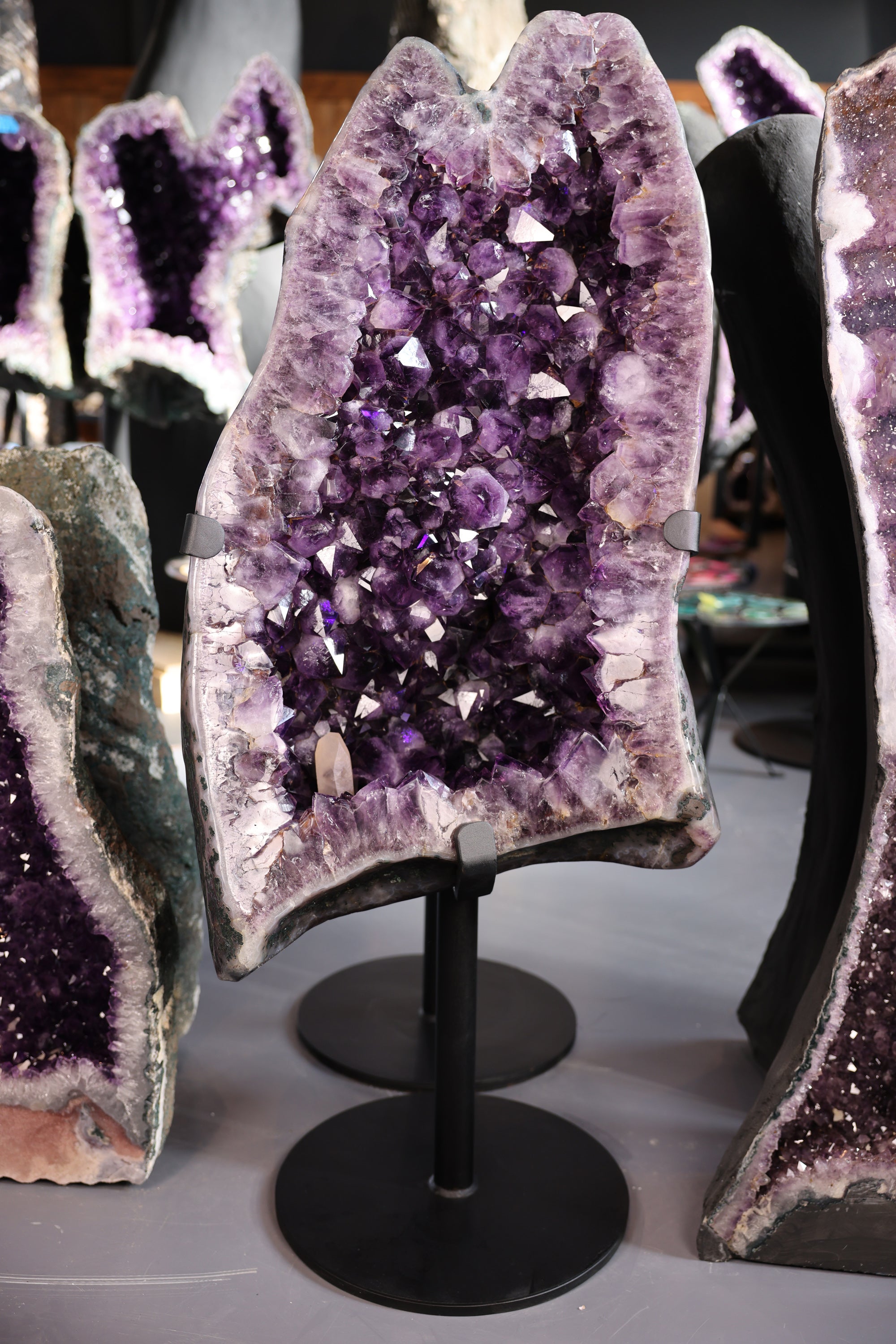 11,8 kg schwere Amethystdruse aus Brasilien mit großen violetten Kristallspitzen, zentralem Calcitkristall und poliertem Achatrand auf Metallstandfuß