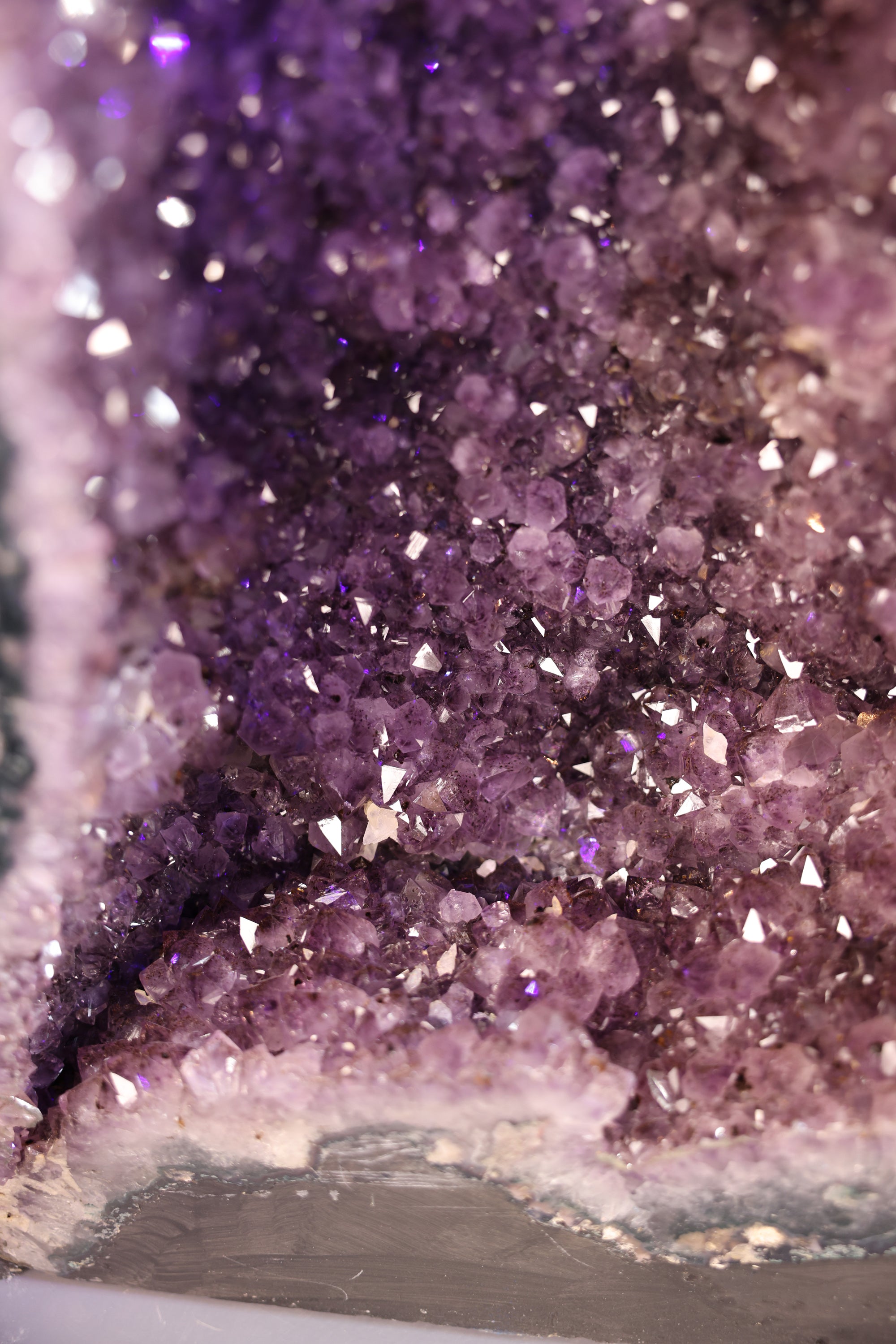Nahaufnahme einer Amethyst-Druse mit violetten Quarzkristallen und sichtbarer Kristallspitzenstruktur.