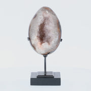 Poliertes Amethyst-Ei aus Uruguay auf Metallständer mit sichtbarer Achatstruktur außen und funkelnder Amethyst-Druse im Inneren.
