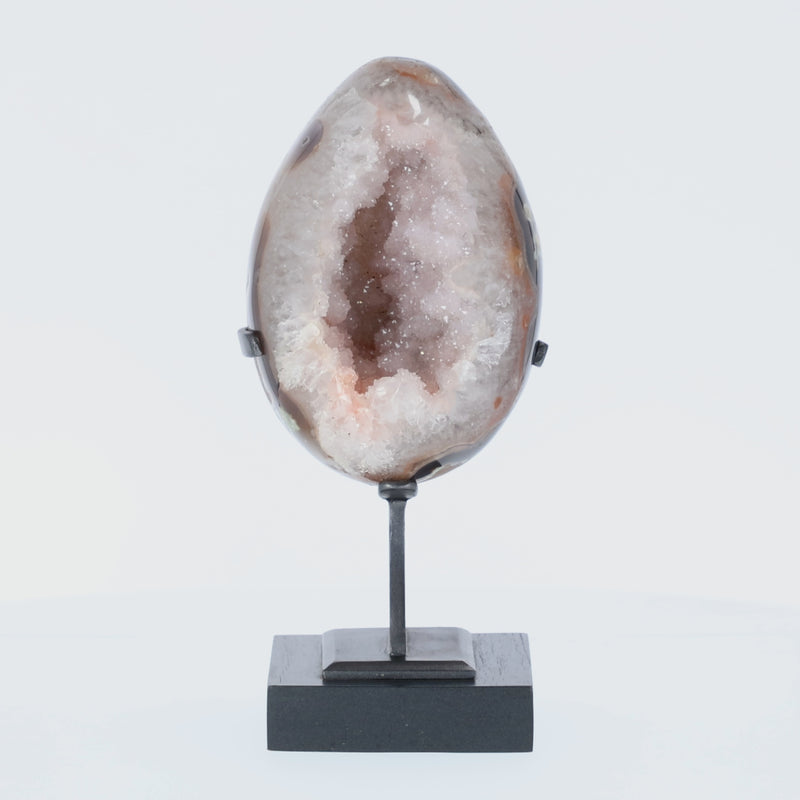 Poliertes Amethyst-Ei aus Uruguay auf Metallständer mit sichtbarer Achatstruktur außen und funkelnder Amethyst-Druse im Inneren.