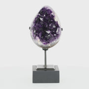 Poliertes Amethyst-Ei aus Uruguay auf Metallständer mit sichtbarer Achatstruktur außen und funkelnder Amethyst-Druse im Inneren.